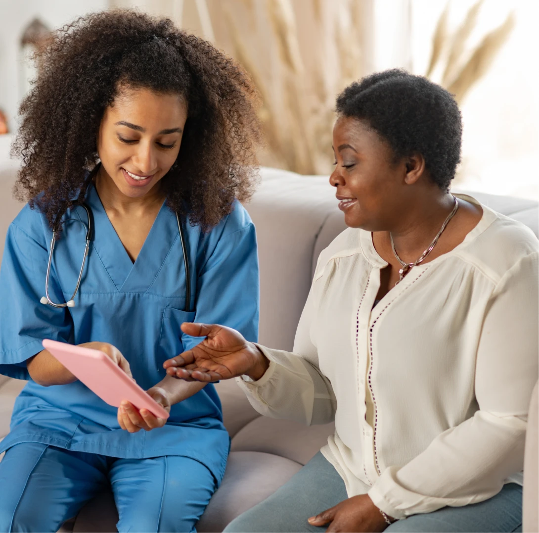 talking-nurse-elderly-dark-skinned-lady-feeling-joyful-while-talking-nurse-showing-her-news-tablet 2 talking-nurse-elderly-dark-skinned-lady-feeling-joyful-while-talking-nurse-showing-her-news-tablet 2